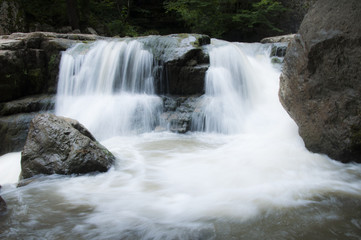 Waterfall with its streams in the forest surrounded with mountai