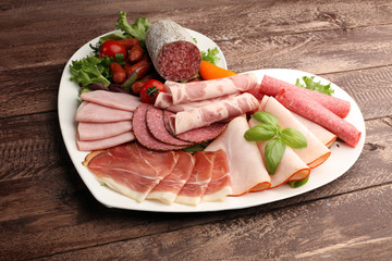 Food tray with delicious salami, pieces of sliced ham, sausage, tomatoes, salad and vegetable - Meat platter with selection