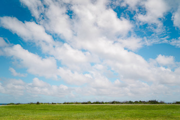 green field and blue sky with dramaty clouds