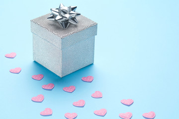 Blue plain background with silver gift and pink hearts