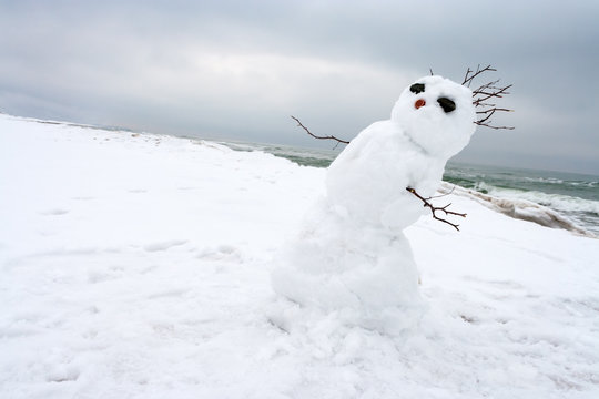 crazy, melting snowman on a winter beach