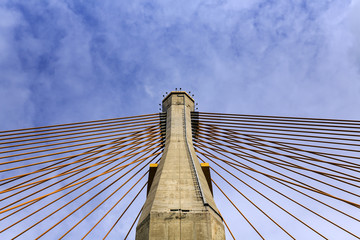 concrete tower and cable bridge with cloud and blue sky