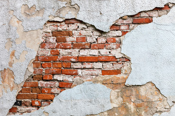 old wall with crumbling plaster and visible masonry of red brick