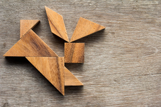 Wooden tangram as running rabbit shape on old wood background