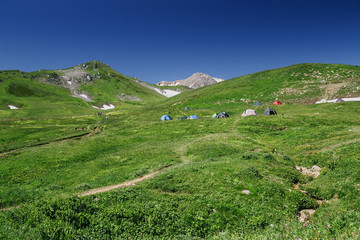 Fototapeta na wymiar Big camp with a lot of tents in alpine meadows