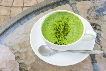 Closeup a cup of matcha latte or green tea on glass table backgr