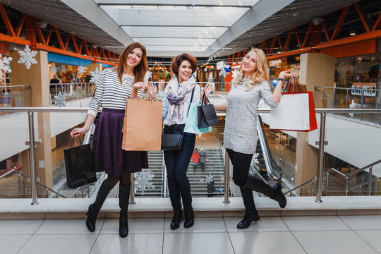 three beautiful young women with shopping bags looking at camera in the mall