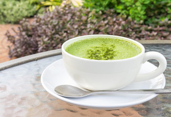 Closeup a cup of matcha latte or green tea on glass table with n