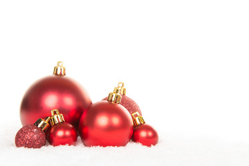 Group of red glass christmas decoration balls in the snow on a white background
