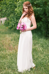 Naklejka na ściany i meble Beautiful bride in white dress in the garden
