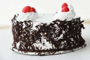 Black forest cake decorated with whipped cream and cherries. Isolated on white background