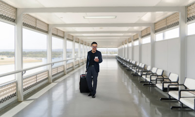 Man on smart phone - young business man in airport. Casual urban professional businessman using smartphone smiling happy inside office building or airport.