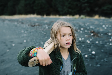Boy with driftwood at riverbank