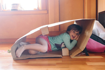 Portrait of girl lying in cardboard box, smiling