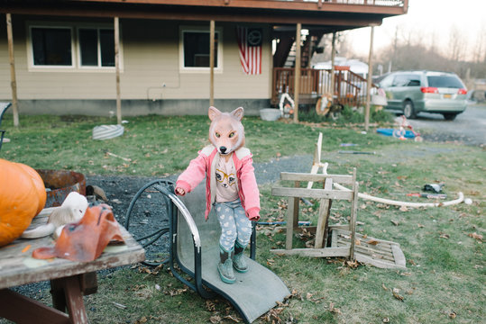 Portrait of girl wearing fox mask, standing in yard