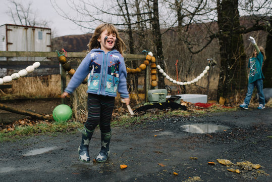Girl playing outdoors, with mud on face, laughing