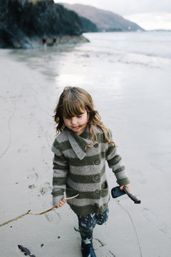 Girl holding stick in hand while walking on beach