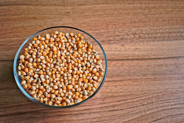 Popcorn kernels in a bowl on a wooden table