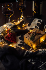 Christmas present with knitted sweater, Christmas lights and two glasses of wine. Celebration. Christmas concept.