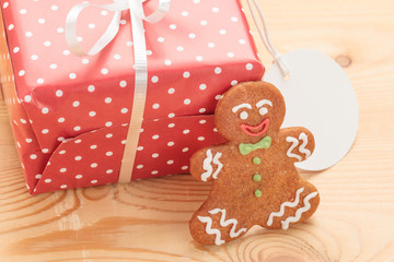 Closeup of gingerbread Christmas cookie with red gift box on wooden background