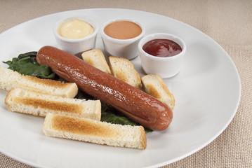 wurstel con salse, spinaci, pane tostato in piatto