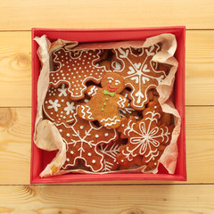 Red box Christmas gingerbread cookies on wooden background. View from above