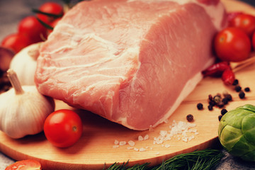 Raw pork on cutting board and vegetables