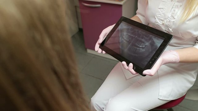 Close-up of doctor looking at human teeth X-ray on the digital tablet. Dentistry.
