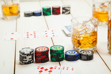 glass of whiskey with ice, game  poker on a white wood table