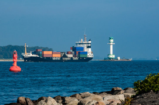 Containerschiff an Leuchtturm und Fahrwassertonne