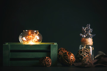 Composition of sparkler, glass vase and decor on dark background