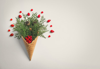 Waffle cone with composition of coniferous branches, berries and strobiles on white background