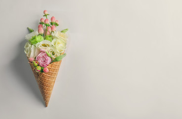 Waffle cone with composition of flowers and branches on white background