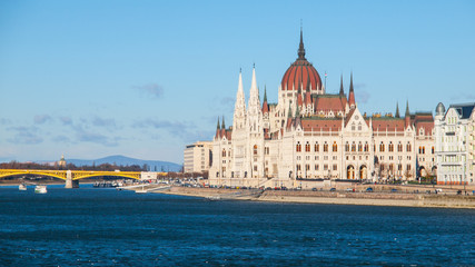 Fototapeta na wymiar Daytime view of historical building of Hungarian Parliament, aka Orszaghaz, with typical symmetrical architecture and central dome on Danube River embankment in Budapest, Hungary, Europe. It is