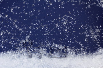 Christmas scene - deer carrying sled in a snowfall. Decoration for the new year of artificial snow and molds for cookies on a dark blue background. Top view, flat lay, copy space