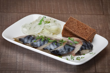 Cold snack - pieces of herring with bread and pickled onion.