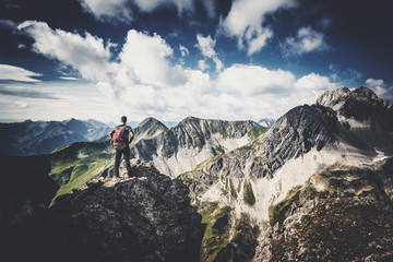 Mann steht auf einsamen Berggipfel in wilder Natur