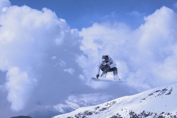 Naklejka na ściany i meble Snowboard rider jumping on mountains. Extreme sport.