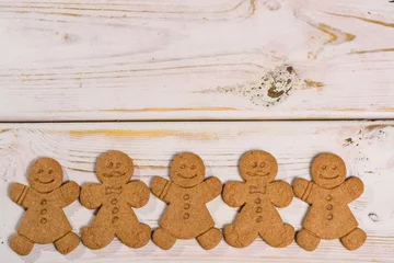 Fotobehang Christmas smiling  gingerbread men on rustic wooden background © barmalini
