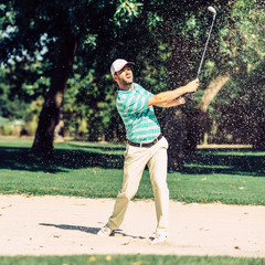 Male golfer . Golfer pulling ball out of sand trap