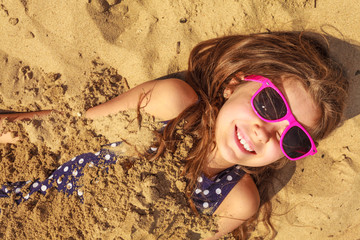 Lovely gorgeous little girl playing with sand.