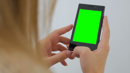 Woman using vertical smartphone with green screen. Close up shot of woman's hands with mobile Close up shot of woman's hands with mobile. White background