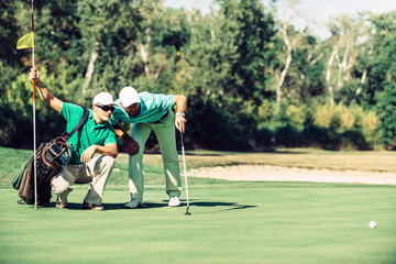 Male golfers. Reading the green. 