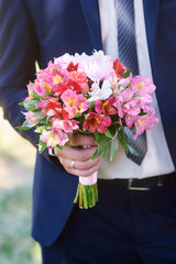 groom holds the brides bouquet in wedding day