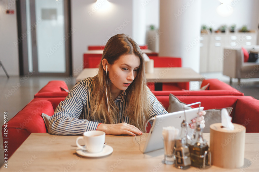 Wall mural surprised armenian girl in cafe using tablet