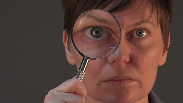 Female tax inspector with magnifying glass looking into papers and documents