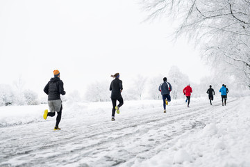 group young people running together snowy trail in winter Park. rear view