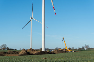 Baustelle einer Windkraftanlage mit Autokran bei blauem Himmel