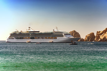 Fototapeta na wymiar Cruise ship sailing near rocks on green ocean