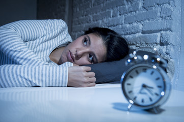 hispanic woman at home bedroom lying in bed late at night trying to sleep suffering insomnia